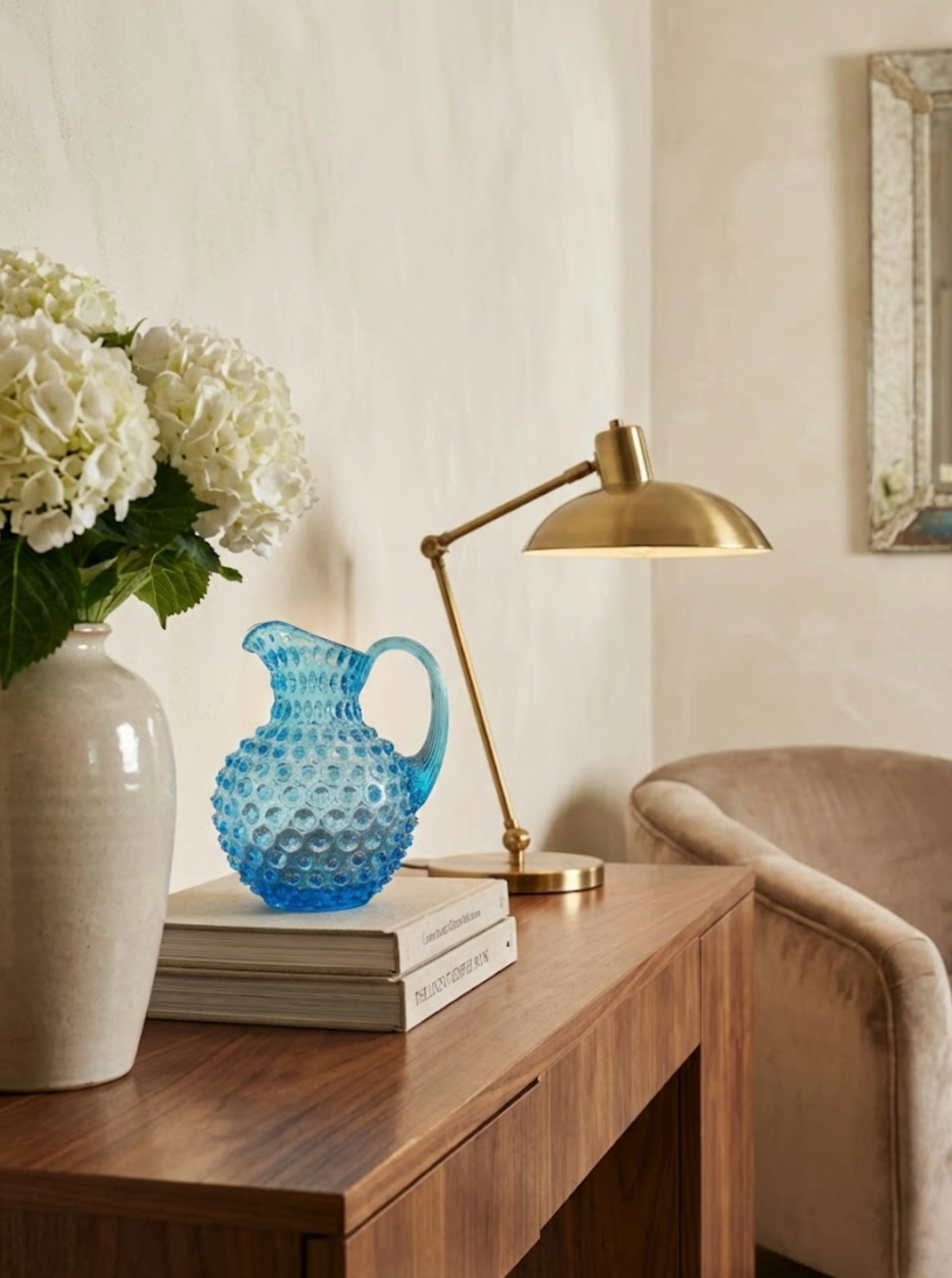 Curated living room with sage green wall, round mirror, and styled console